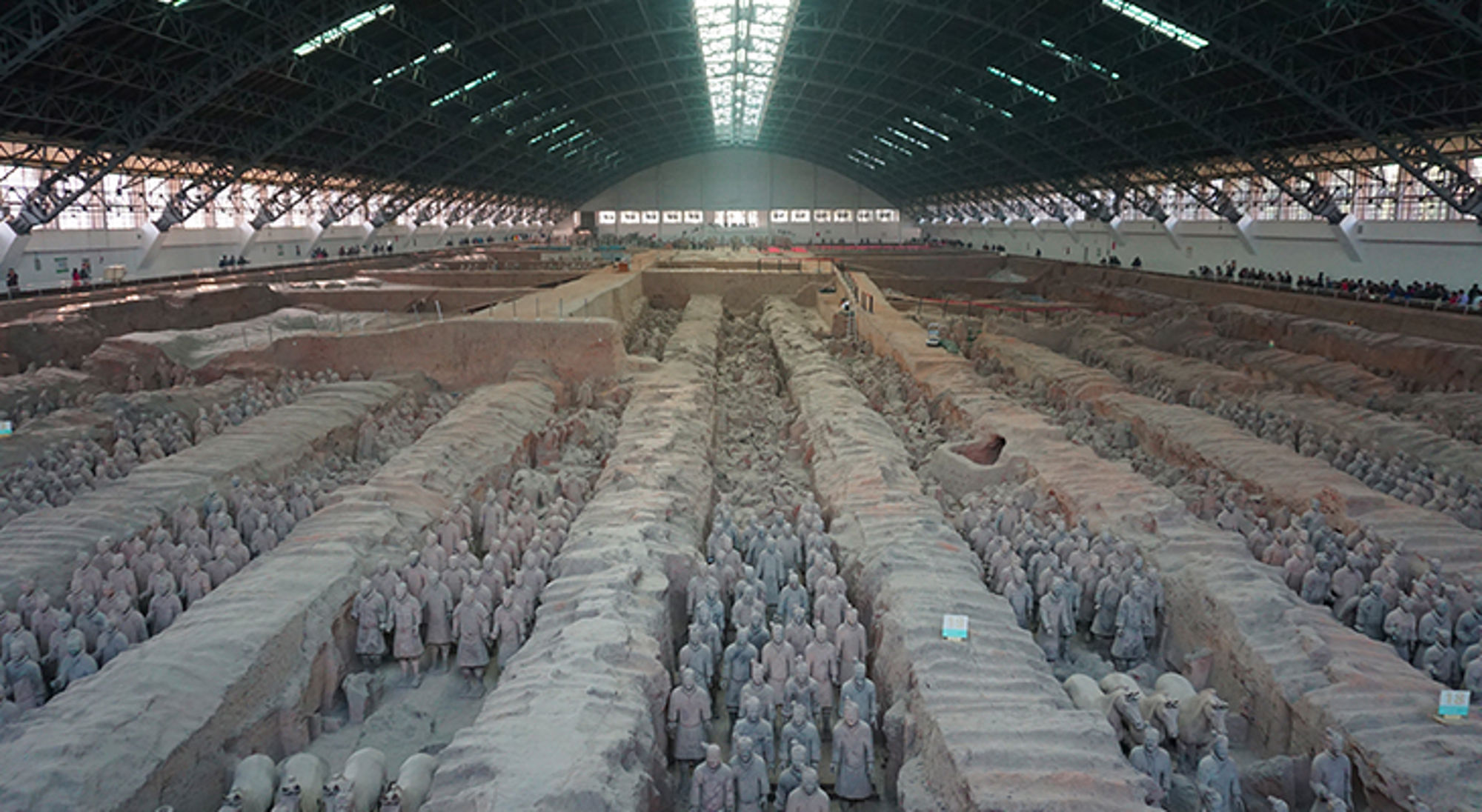Terracottaleger in Xi’an: rijen kleisoldaten en paarden in opgegraven grafkuilen onder een grote hal.