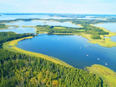 de Mazurische Meren in Polen met eilanden, bossen en zeilboten op het water.