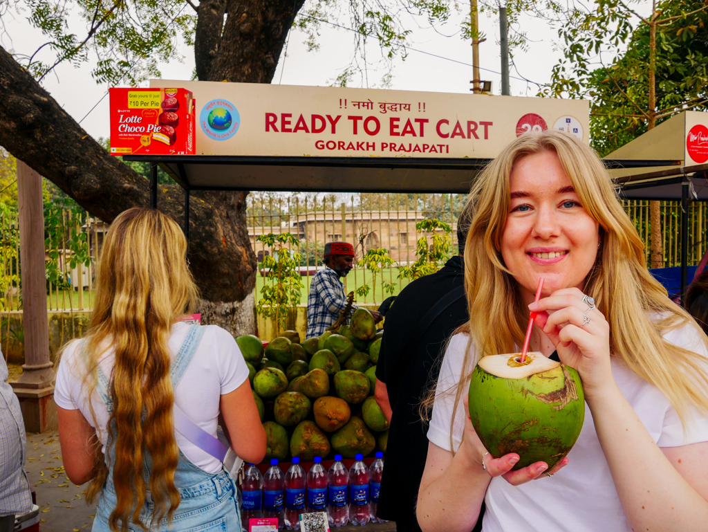 Reiziger drinkt kokosnoot bij een streetfoodkraam tijdens de 22-35ers reis India.