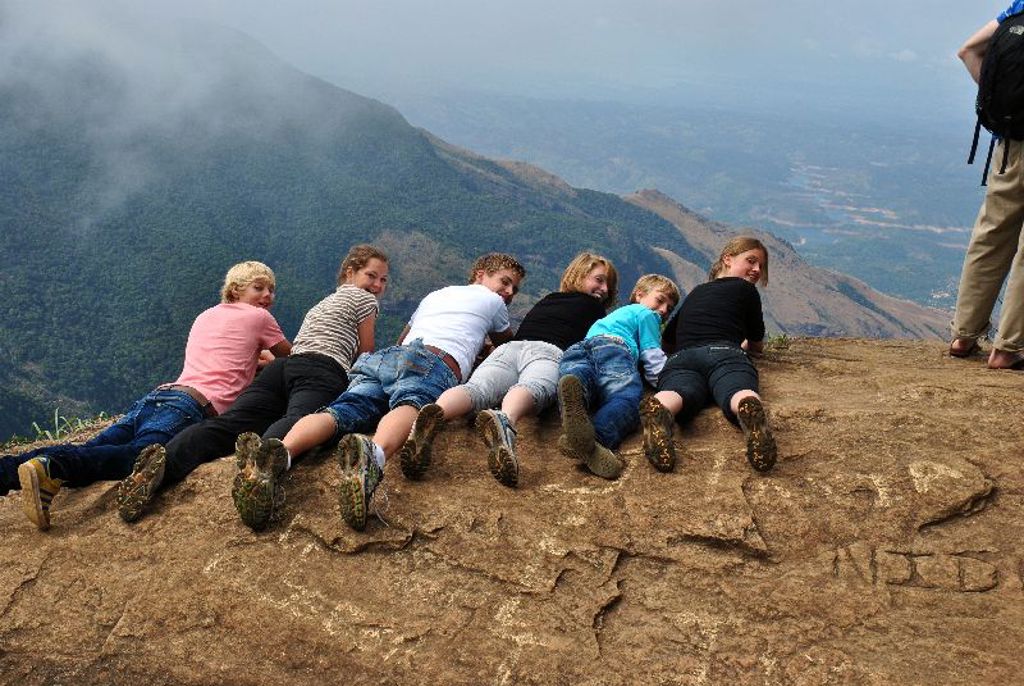 Kinderen liggen op een rots en kijken uit over de bergen tijdens een familiereis in Sri Lanka.