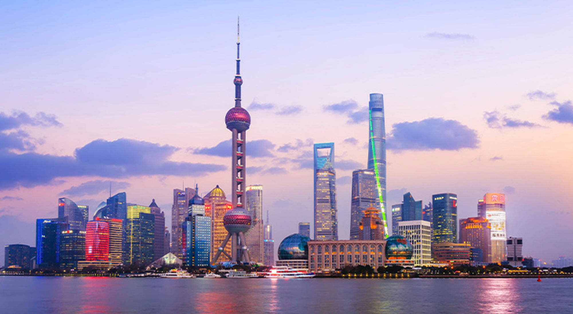 Shanghai China Skyline van Shanghai bij zonsondergang met de Oriental Pearl Tower en wolkenkrabbers langs de Huangpu-rivier.
