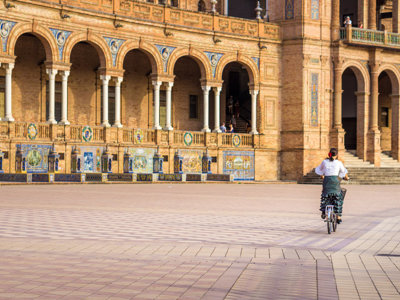 Fietser op Plaza de España in Sevilla, met bogen en kleurrijke tegels in Andalusië.