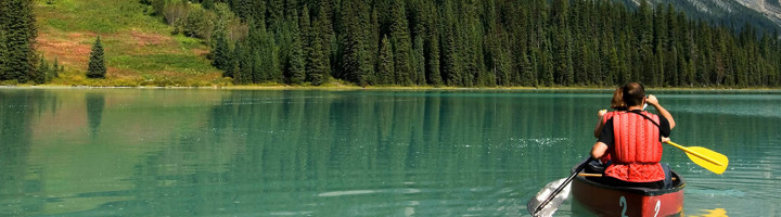 Kanovaren op een turquoise bergmeer in Canada, omringd door dennenbossen.