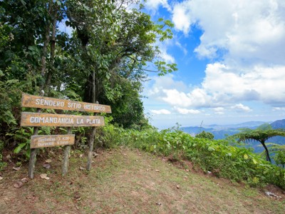 Wandelpadbord naar Comandancia La Plata in de Sierra Maestra, Cuba, met uitzicht op groene bergen.