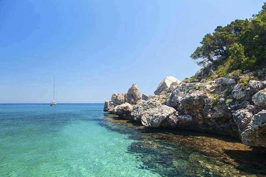 Rotsachtige kust met kliffen en helderblauw zeewater op Sardinië, Italië.