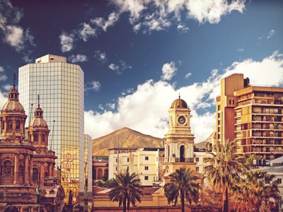 Skyline van Santiago de Chile met historische kerktorens, moderne hoogbouw en Andes op de achtergrond.