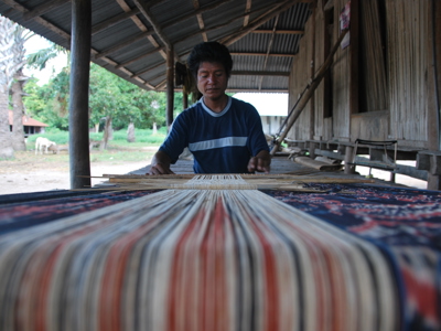Man weeft traditioneel textiel op een weefgetouw tijdens de route Timor, Sumba & Bali (22 dagen).