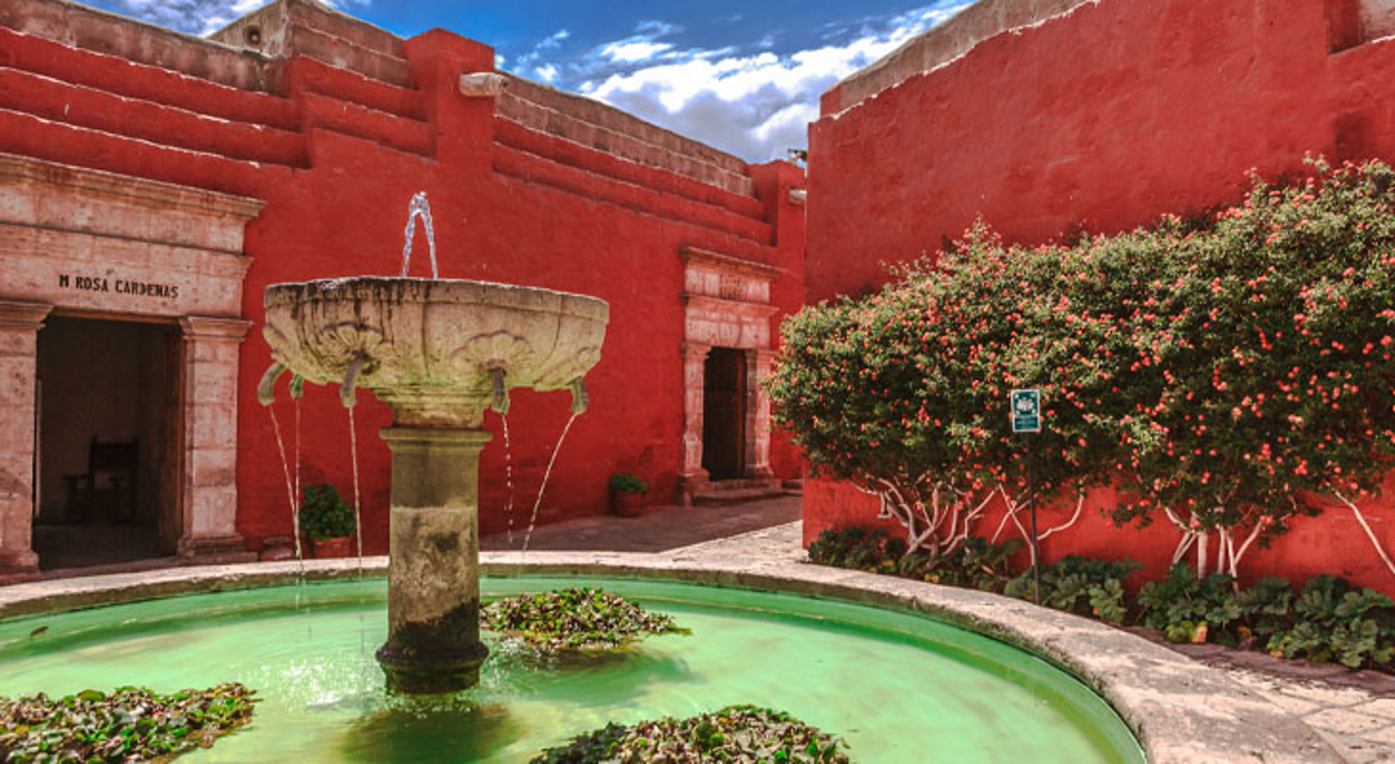 Fontein in het Santa Catalina-klooster in Arequipa, Peru, met rode muren en groene waterbassin.