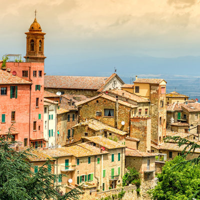 Toscaans heuveldorp met kleurrijke huizen en kerktoren, uitzicht over het landschap tijdens een fietsvakantie in Toscane.