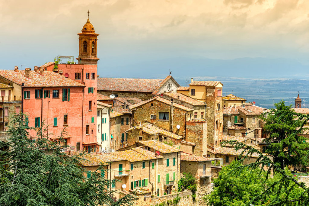 Toscaans heuveldorp met kleurrijke huizen en kerktoren, uitzicht over het landschap tijdens een fietsvakantie in Toscane.