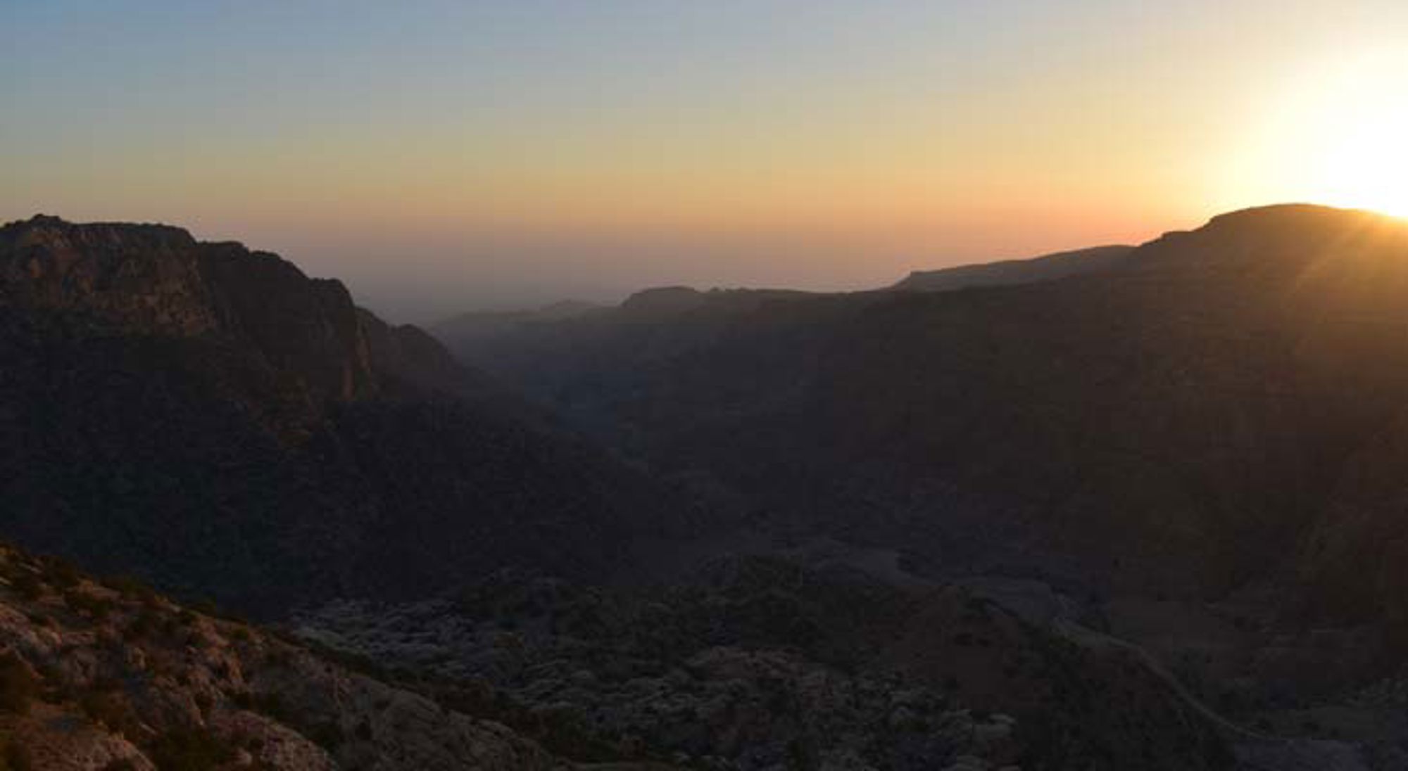 Zonsondergang Dana Natuurreservaat Jordanië Panoramisch uitzicht op de Jordaanse woestijn met rotsachtige heuvels onder een heldere lucht.