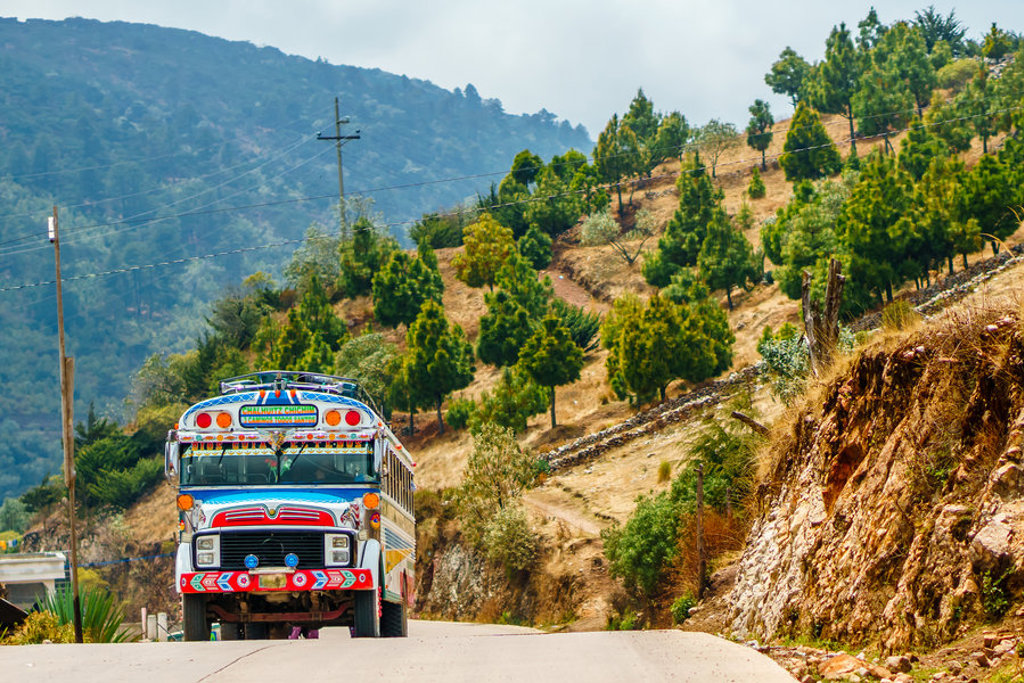Kleurrijke chickenbus op bergweg in Guatemala tijdens groepsrondreis naar Copán.