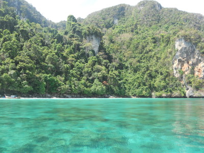 Turquoise zee bij een groen, rotsachtig eiland voor de kust van Phuket, Thailand.