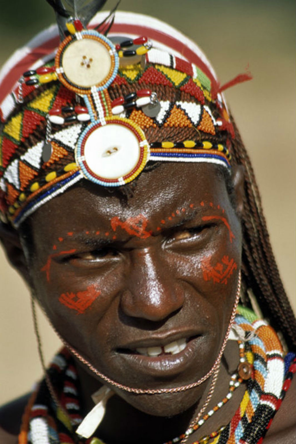 Portret van een Maasai-man met traditionele kralenhoofdband en gezichtsbeschildering in Kenia.