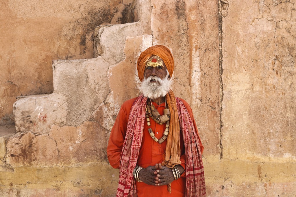 Portret van een sadhu in oranje kleding bij een paleismuur in Rajasthan, India.