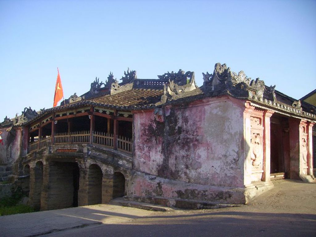 Oude Japanse brug in Hoi An, Vietnam, met versierde dakrand en Vietnamese vlag.
