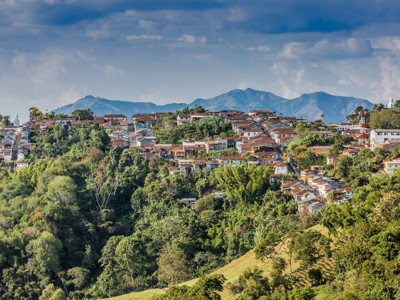Heuvelstadje in Colombia met kleurrijke huizen tussen groene bergen en wolkenlucht.