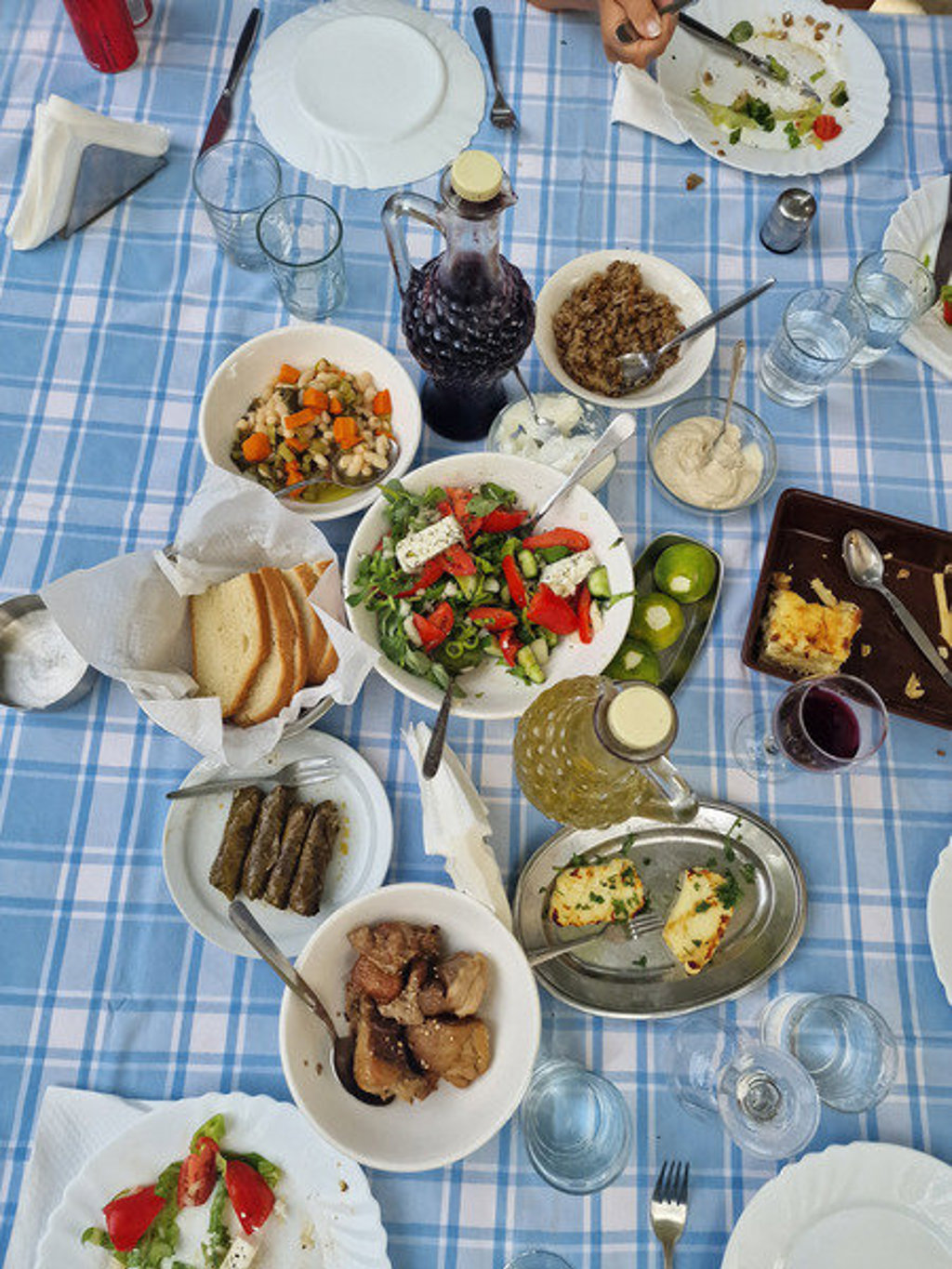 Cypriotische mezze op tafel met salade, brood, vlees en wijn tijdens een wandelvakantie op Cyprus.