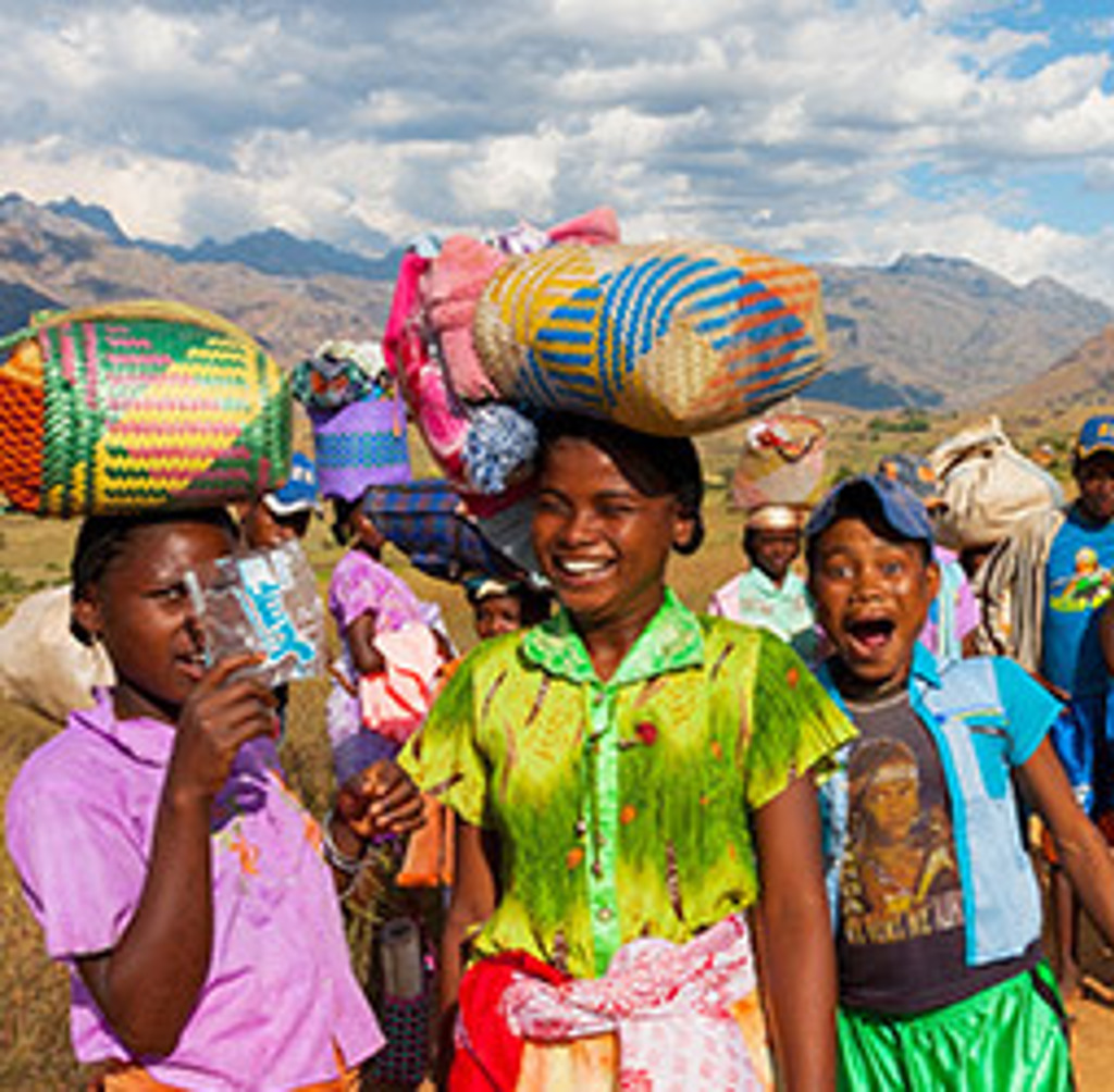 Vrolijke marktlopers met kleurrijke manden in het berglandschap van Madagascar, tijdens een familiereis.