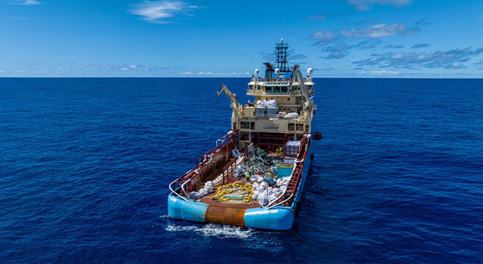 Schip op open zee met dek vol verzameld plastic afval voor recycling en opruiming van oceaanvervuiling.