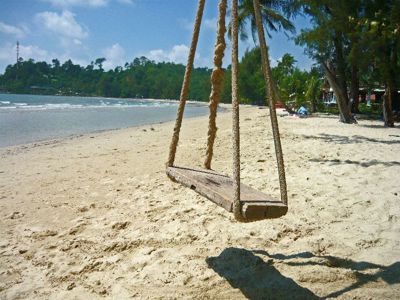 Houten schommel aan palmbomen op een rustig zandstrand in Cambodja of Thailand.
