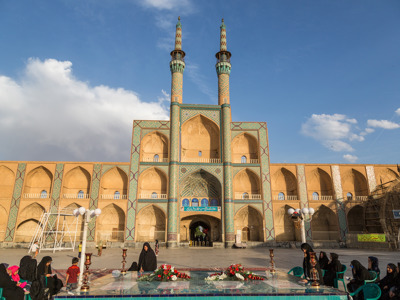Binnenplaats van de Amir Chakhmaq-moskee in Yazd, Iran, met twee minaretten en mozaïekdecoratie.