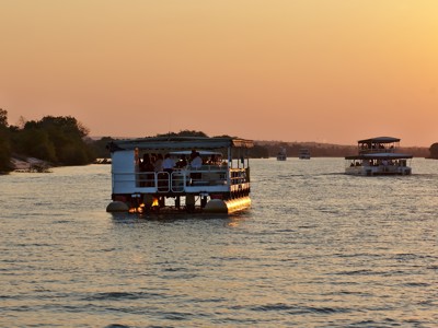 Zonsondergangcruise op de Zambezi-rivier bij Victoria Falls, met boten op het water.