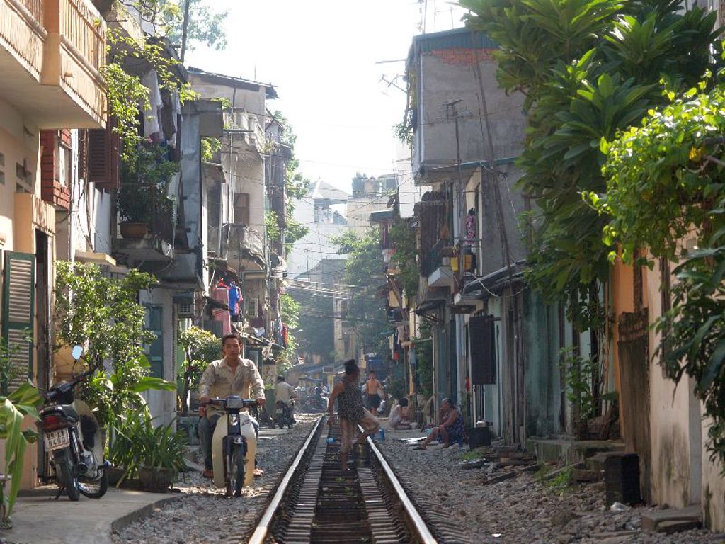 Spoorlijn door een smalle straat met huizen en scooters in Hanoi, Vietnam, tijdens een 22-35ers reis.