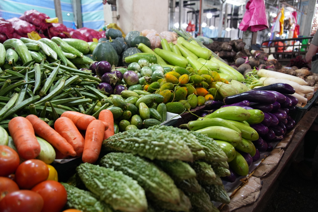 Groentestalletje op een lokale markt in Maleisië tijdens een familiereis, met aubergines, okra, wortels en komkommers.