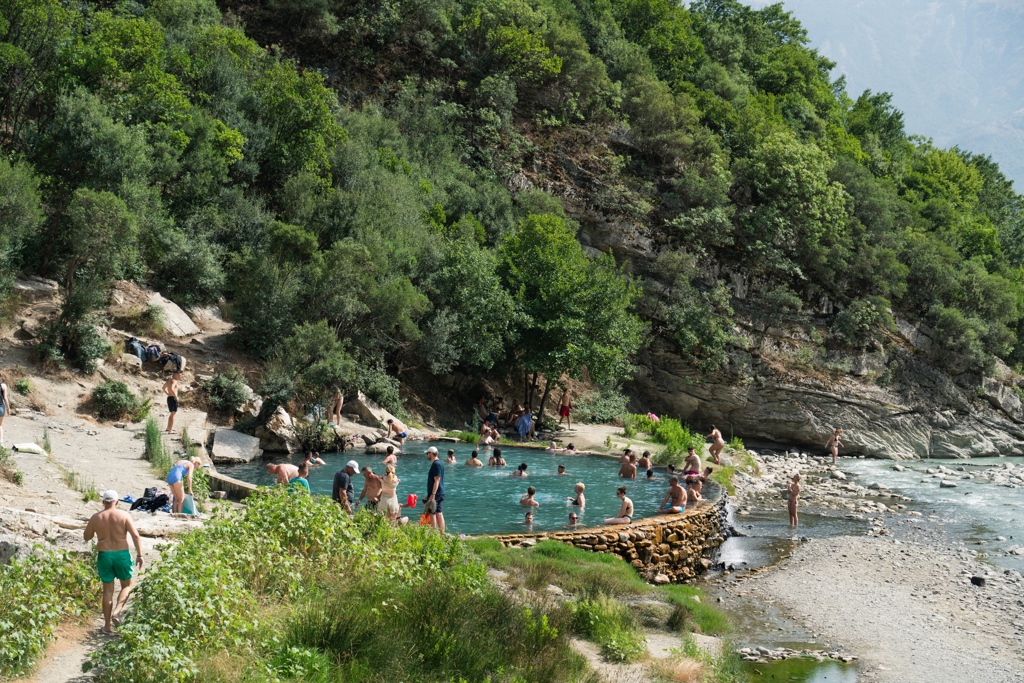 Badgasten zwemmen in een natuurlijke rivierpool tussen groene rotswanden in Albanië.