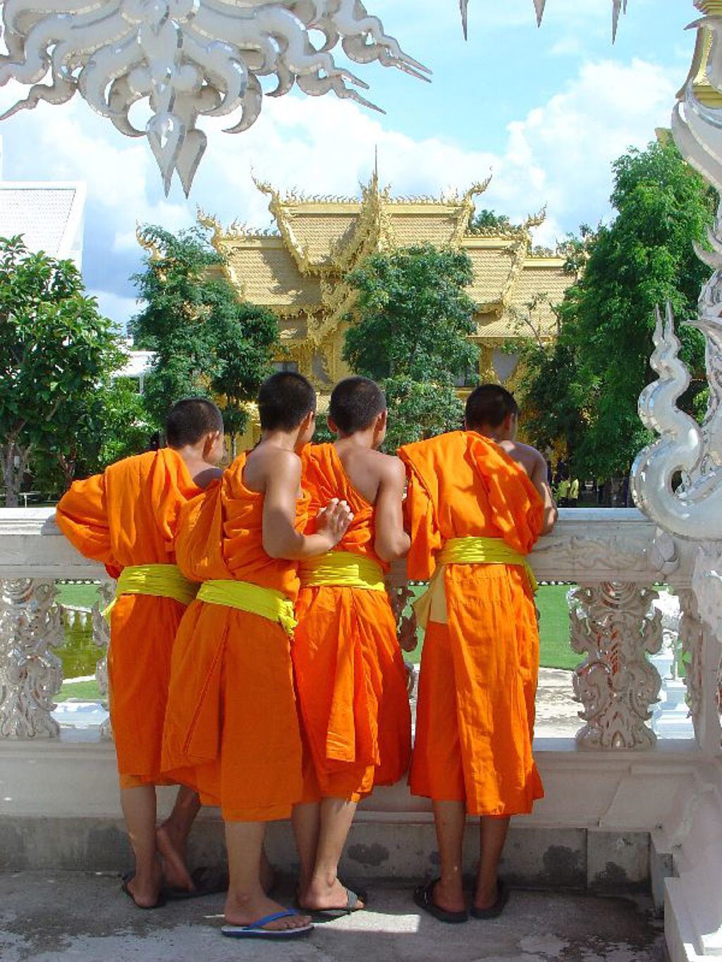 Jonge boeddhistische monniken in oranje gewaden bij een tempel in Thailand tijdens familiereis Noord en Zuid.