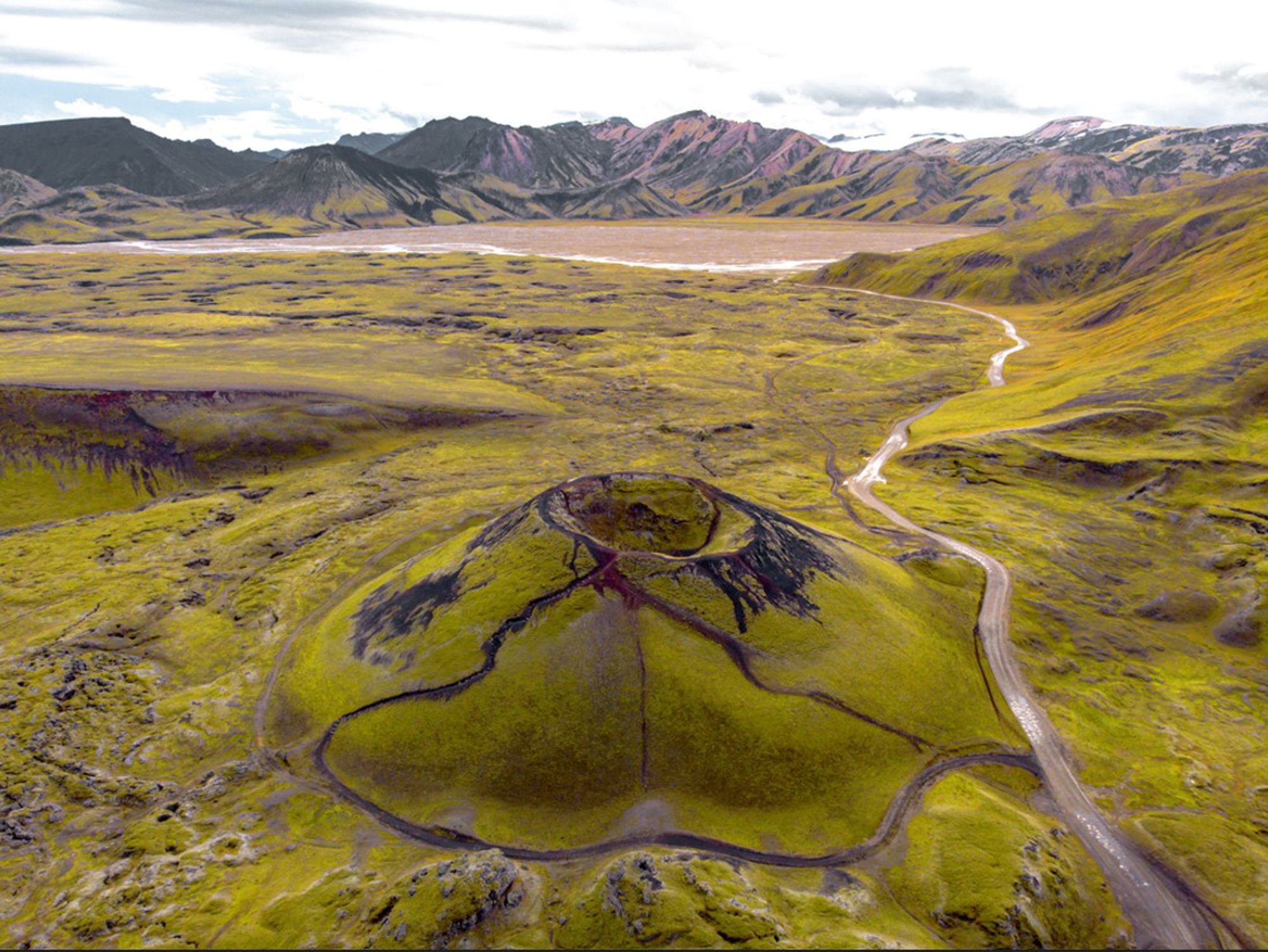 een groene vulkaankrater in het Landmannalaugar-gebied op IJsland, met bergen op de achtergrond.