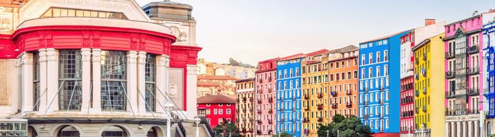 Kleurrijke gevels langs de rivier in Bilbao, met de Mercado de la Ribera op de voorgrond.