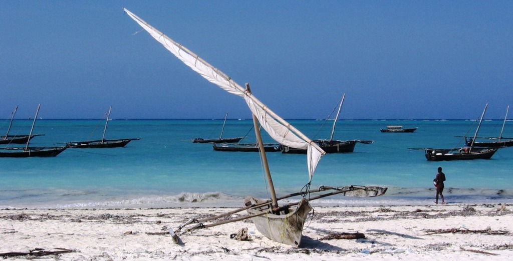 Traditionele dhow zeilboten voor de kust van Zanzibar met wit zandstrand en turquoise zee.