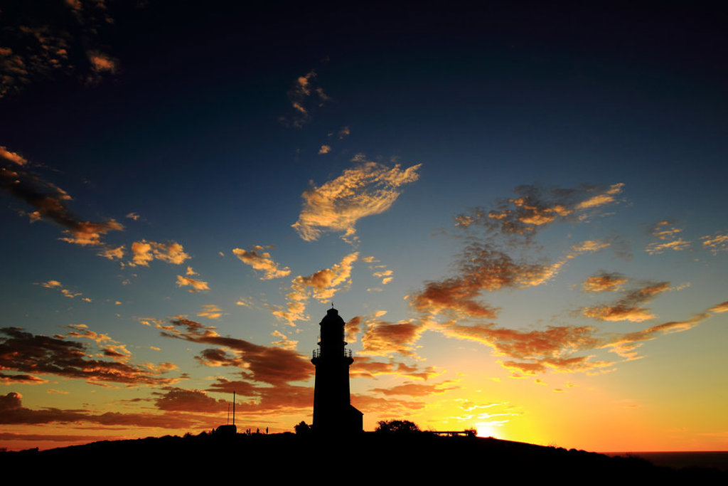 Vuurtoren in silhouet bij zonsondergang aan de kust van West-Australië tijdens een groepsrondreis.