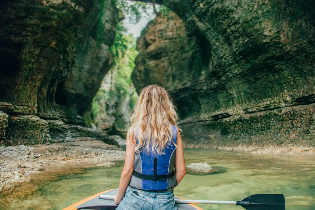 Vrouw op een raft in een smalle kloof met rotswanden en helder water in Georgië.
