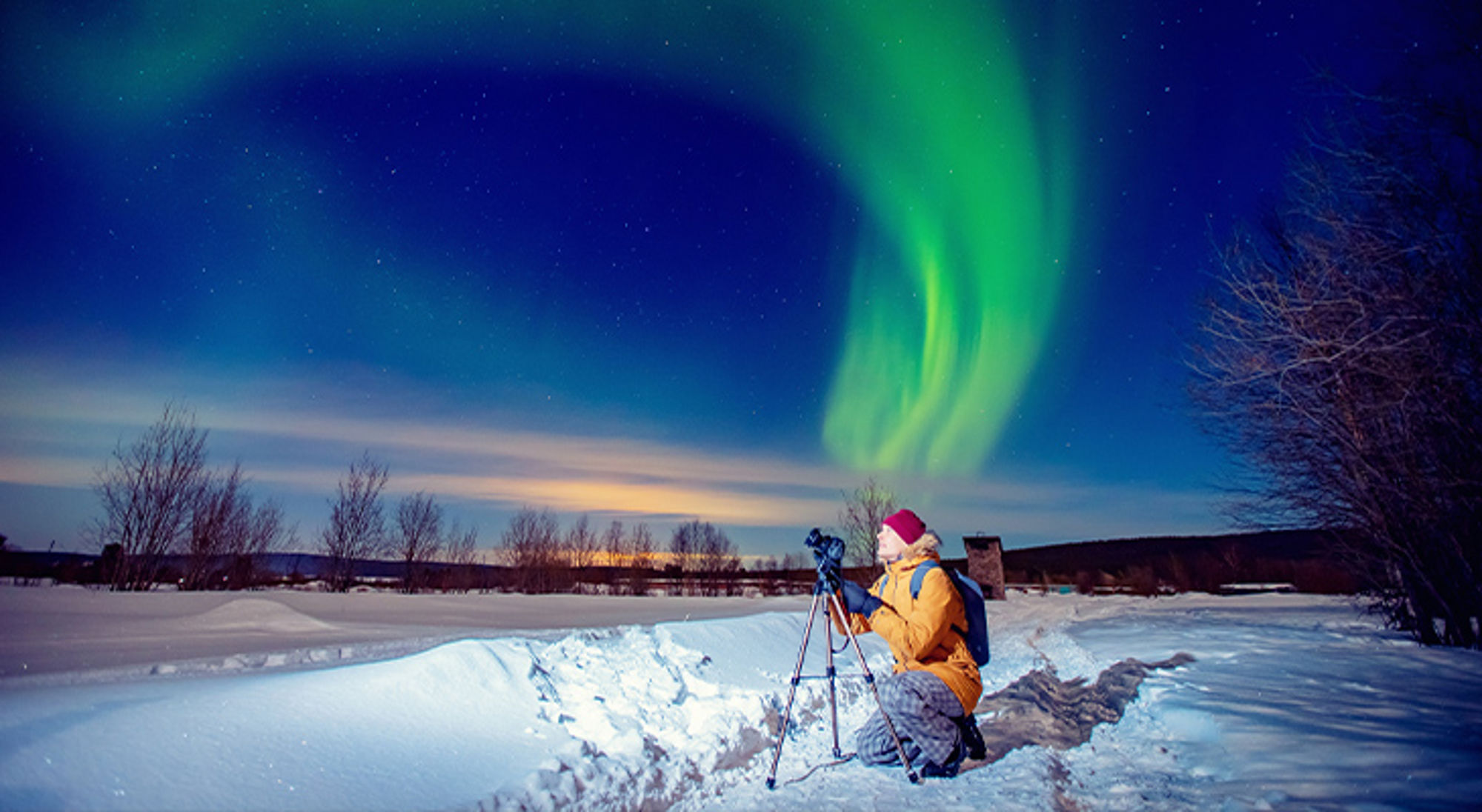 Noorderlicht fotograferen Fotograaf in sneeuwlandschap maakt foto van het noorderlicht onder een sterrenhemel.