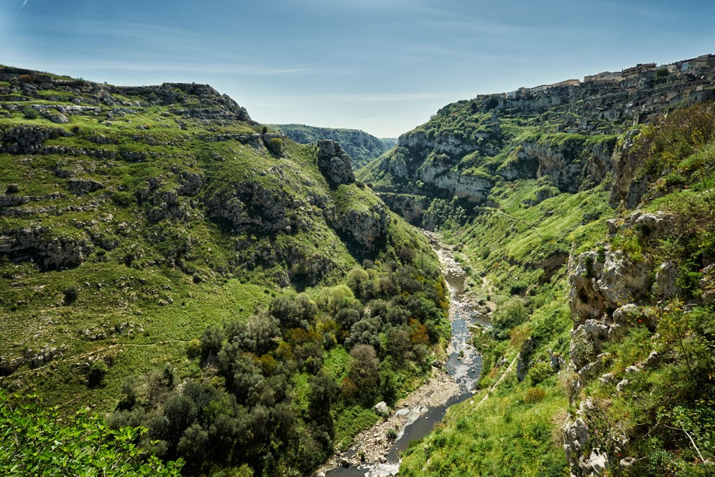 Groene kloof met rivier en rotswanden bij Matera, tijdens wandelvakantie in Puglia, Italië.