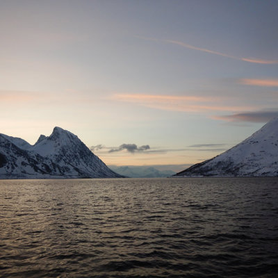 Besneeuwde bergen langs een Noorse fjord bij zonsondergang tijdens de groepsrondreis met zeilschip Antigua.