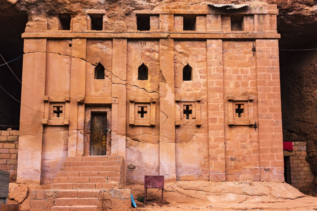 Rotskerk in Lalibela, Ethiopië, uitgehouwen in steen met kruismotieven en kleine ramen.