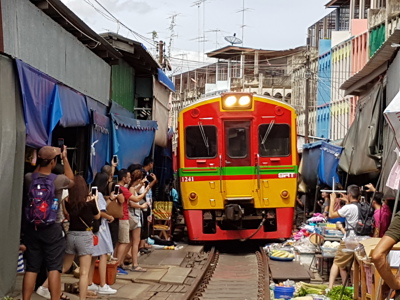 Trein op de Maeklong Railway Market in Zuid-Thailand, tussen marktkramen en toeschouwers.