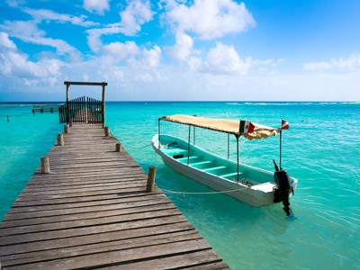 Houten steiger met bootje in helderblauw water aan de Mexicaanse kust, route Mexico.
