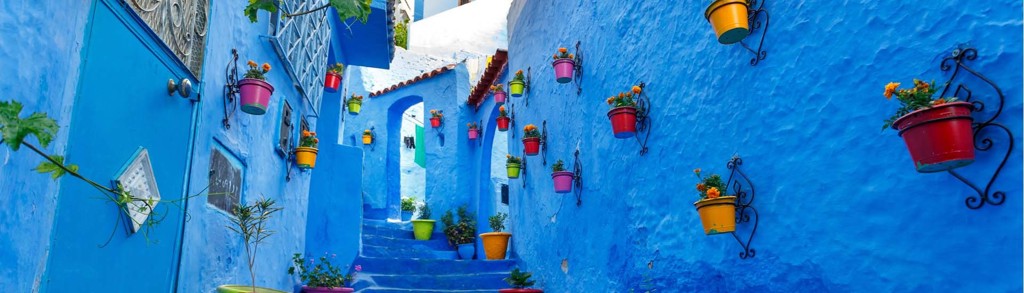 Blauwe straat met trappen en kleurrijke bloempotten in Chefchaouen, Marokko.