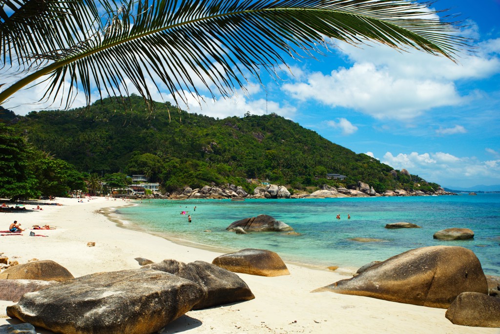 Tropisch strand in Zuid-Thailand met palmbomen, rotsen en helderblauw zeewater tijdens familiereis.