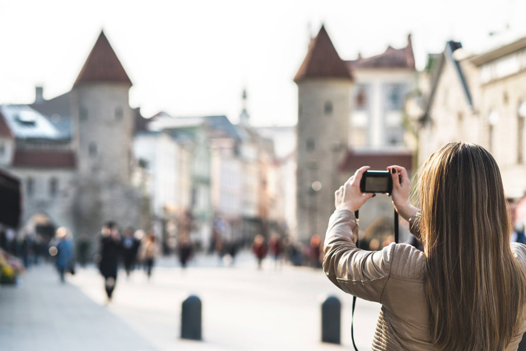 Toerist fotografeert middeleeuwse stadspoort in Tallinn tijdens familiereis Polen en Baltische Staten.