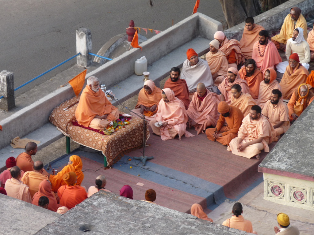 Hindoeïstische monniken luisteren naar een spirituele les op een terras in India.