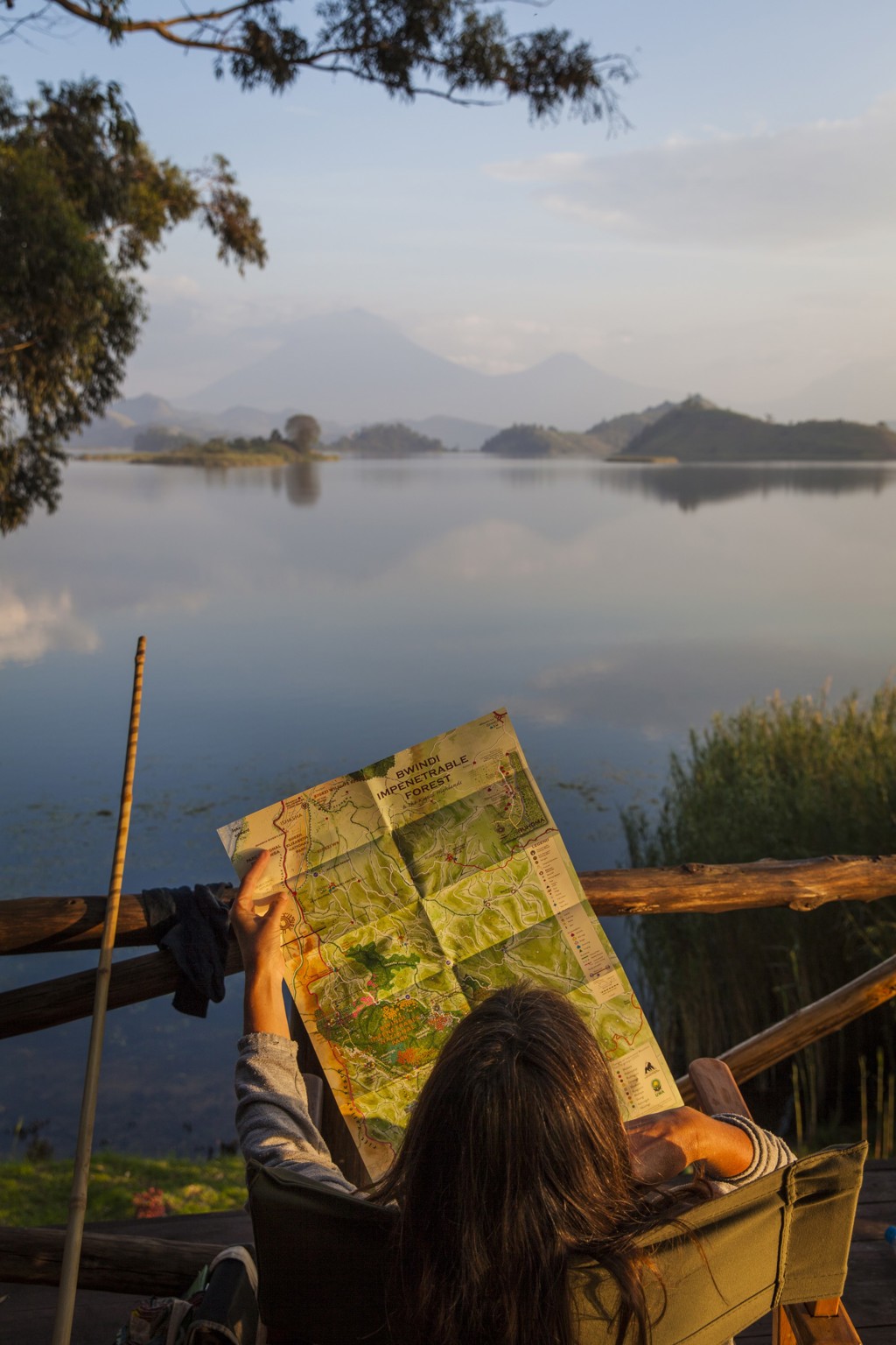 Reiziger bekijkt een kaart van Bwindi Impenetrable Forest aan een rustig meer in Oeganda.