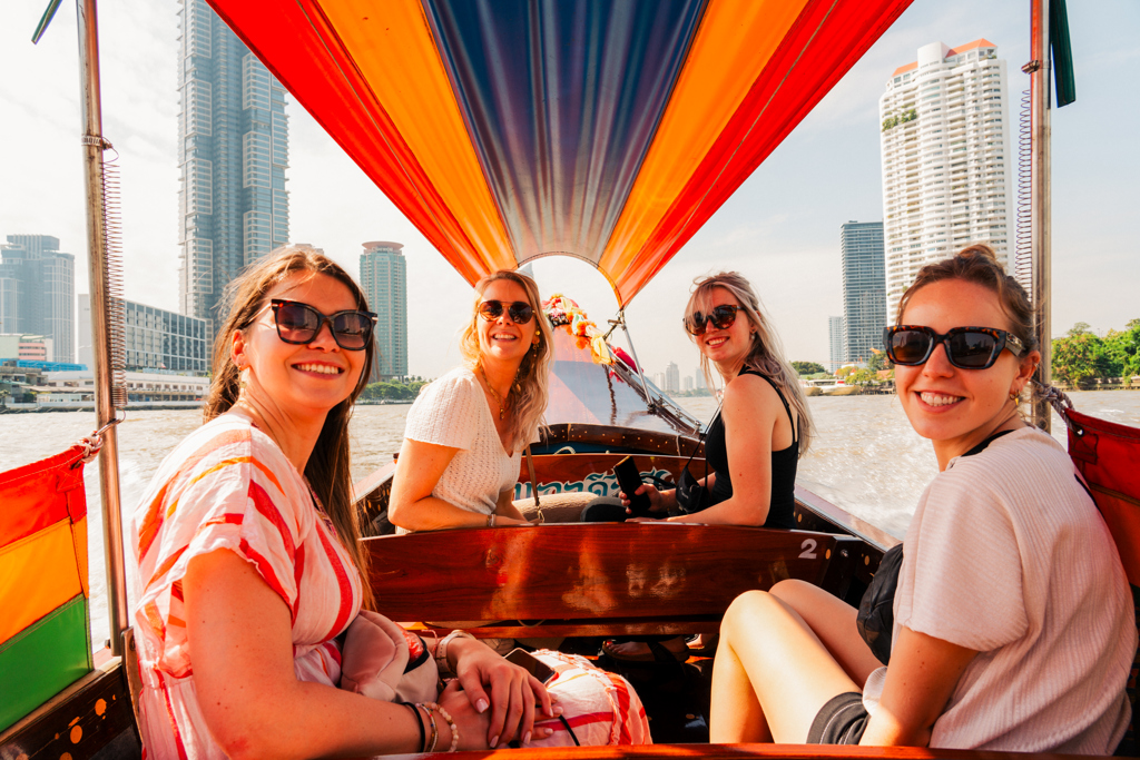 Vriendengroep vaart met een longtailboot over de rivier in Bangkok tijdens een 22-35ers reis Thailand.