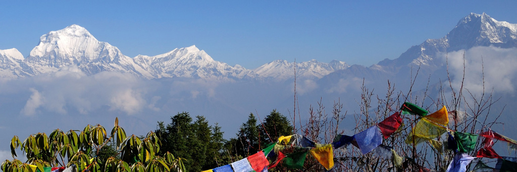 Besneeuwde Himalaya in Nepal met kleurrijke gebedsvlaggen op de voorgrond.