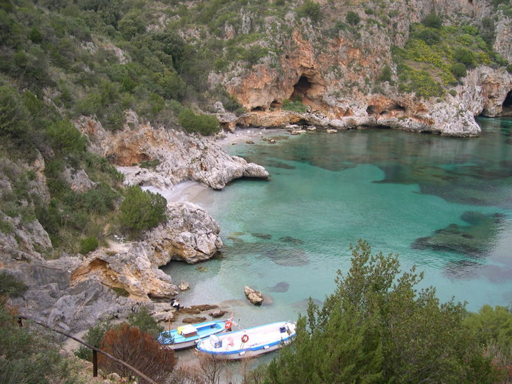 Rotsachtige baai met turquoise water en bootjes aan de kust in Zuid-Italië, Cilento.